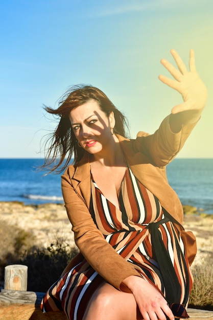 Jovem loira na praia e se protegendo com a mão no rosto Foto de alta qualidade