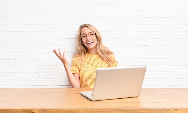 jovem loira no laptop, sentindo-se feliz e alegre