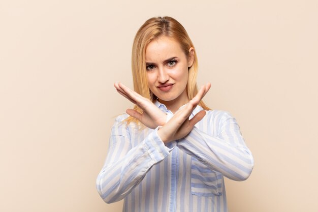 Jovem loira parecendo irritada e cansada de sua atitude, dizendo chega! mãos cruzadas na frente