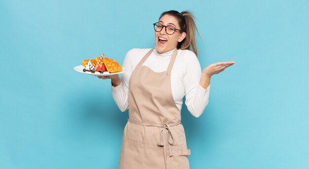 Jovem loira se sentindo feliz, animada, surpresa ou chocada, sorrindo e espantada com algo inacreditável