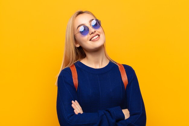 Jovem loira se sentindo feliz, orgulhosa e esperançosa, pensando ou pensando