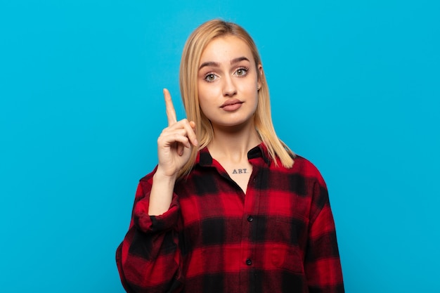 Jovem loira se sentindo um gênio, segurando o dedo com orgulho no ar depois de perceber uma ótima ideia, dizendo eureka