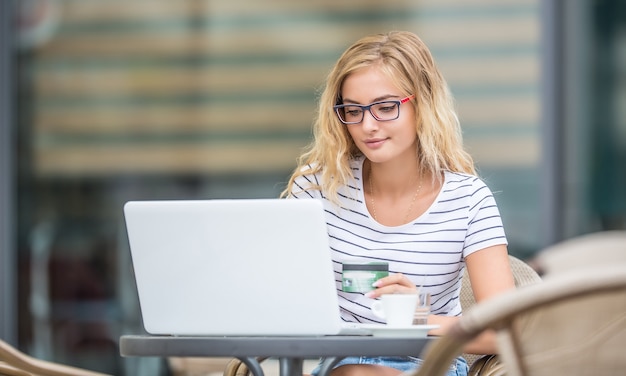 Jovem loira segurando um cartão de crédito e usando um laptop