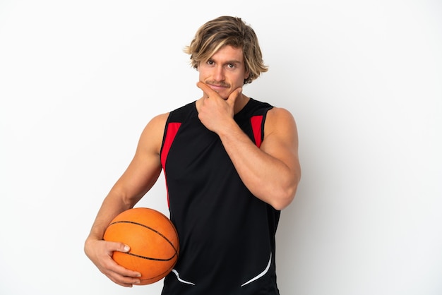 Jovem loira segurando uma bola de basquete isolada no fundo branco pensando