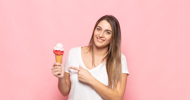 Jovem loira sorrindo alegremente, sentindo-se feliz e apontando para o lado e para cima, mostrando o objeto no espaço da cópia