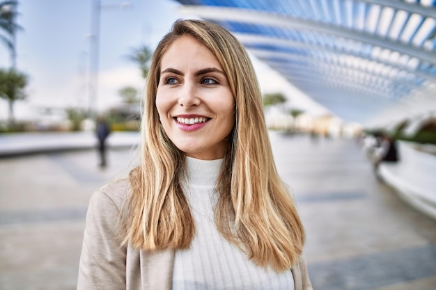 Jovem loira sorrindo confiante na rua