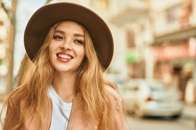 Jovem loira sorrindo feliz em pé na cidade.