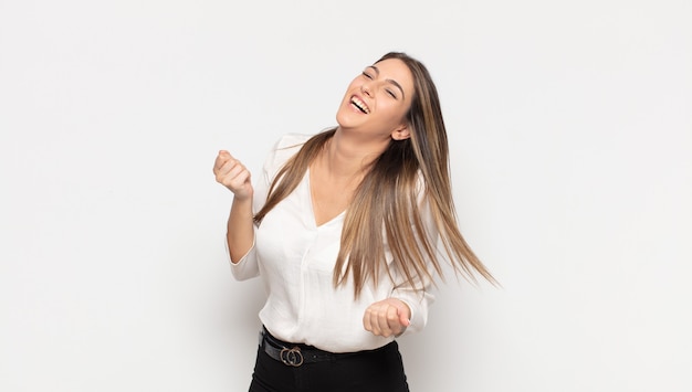 Jovem loira sorrindo, se sentindo despreocupada, relaxada e feliz, dançando e ouvindo música, se divertindo em uma festa