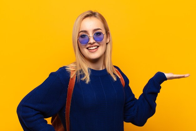 Jovem loira sorrindo, sentindo-se confiante, bem-sucedida e feliz, mostrando o conceito ou ideia no espaço da cópia ao lado