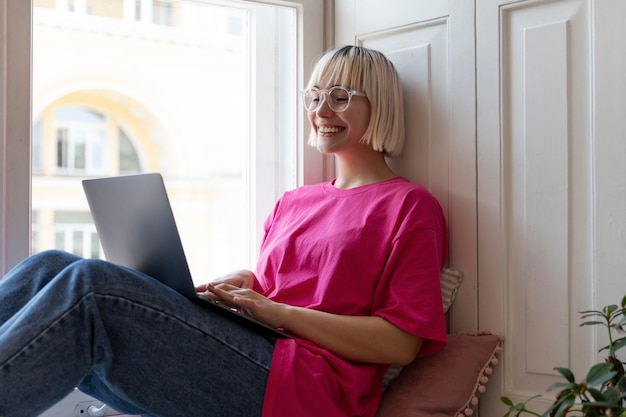Foto jovem loira trabalhando em casa em seu laptop