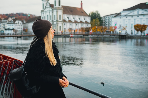 Jovem loira turista com casaco andando no frio de outono na cidade da Europa, aproveitando a viagem