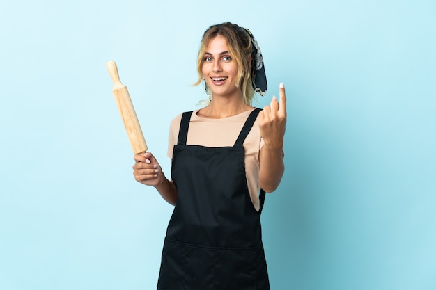 Jovem loira uruguaia cozinhando isolada fazendo gesto de vir