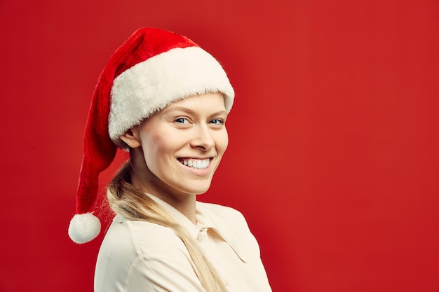 Jovem loira usando chapéu de Papai Noel no vermelho