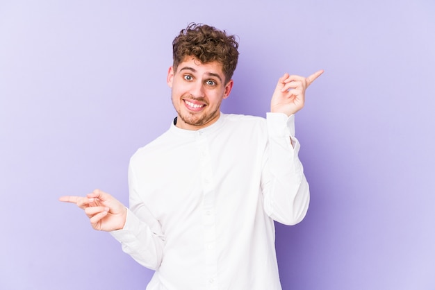 Jovem loiro encaracolado homem caucasiano isolado apontando para diferentes espaços de cópia, escolhendo um deles, mostrando com o dedo.