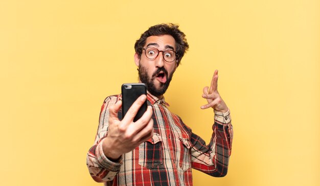 Jovem louco barbudo com expressão feliz e segurando um telefone