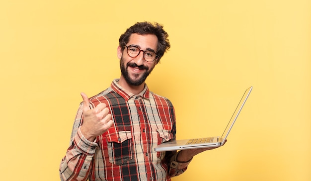 Jovem louco barbudo com expressão feliz e um laptop