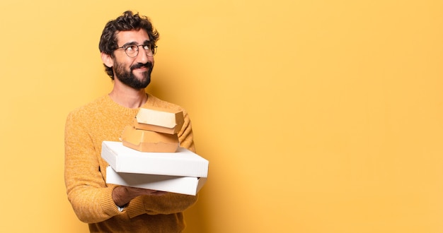 Jovem louco barbudo comendo fast food com um espaço de cópia