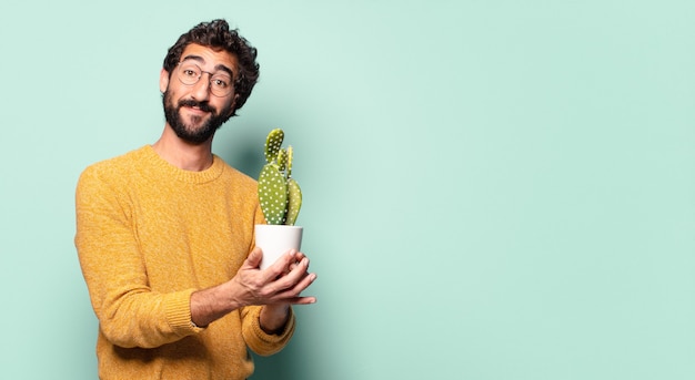 Jovem louco barbudo segurando uma planta de cacto