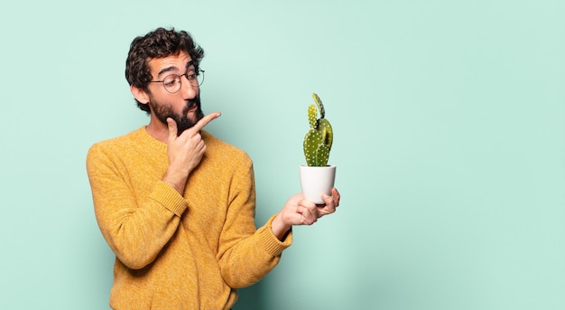 Jovem louco barbudo segurando uma planta de cacto