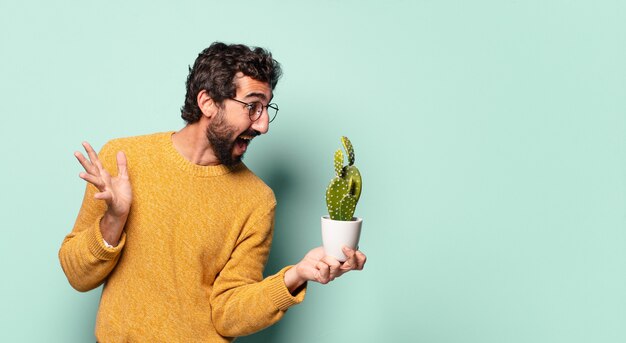 Jovem louco barbudo segurando uma planta de cacto