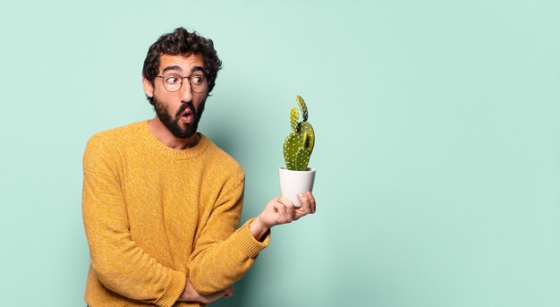 Jovem louco barbudo segurando uma planta de cacto