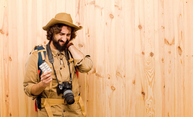 Jovem louco explorador com chapéu de palha e mochila na parede de madeira