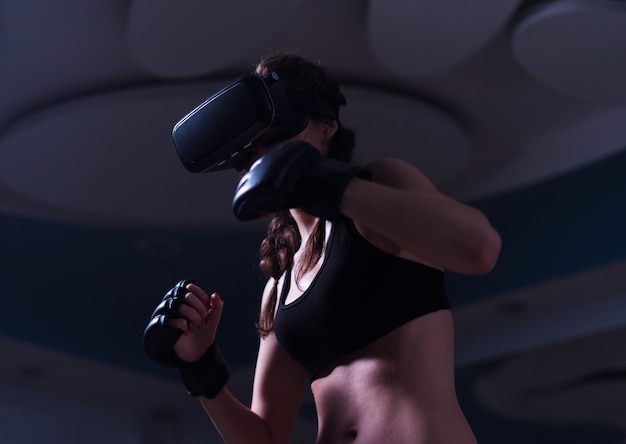Jovem lutador boxeador em forma de garota com óculos de realidade virtual e luvas de boxe em treinamento