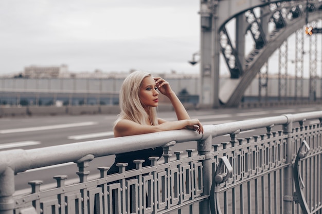 Jovem luxuosa mulher loira ficando na ponte e sonhando