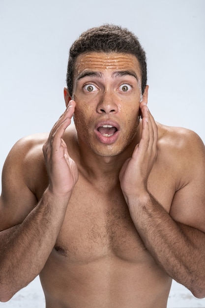 Foto jovem macho abrindo a boca e tocando seu rosto ficando horrorizado