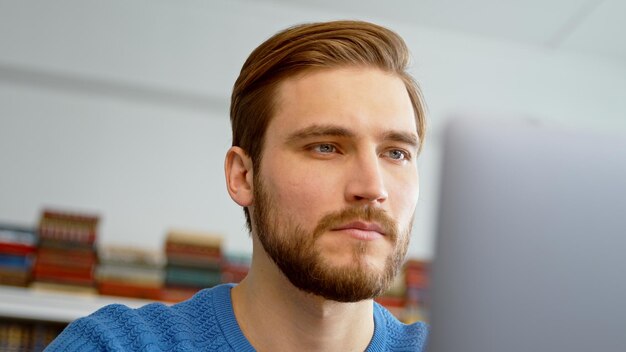 Jovem macho navegando na internet usando um laptop