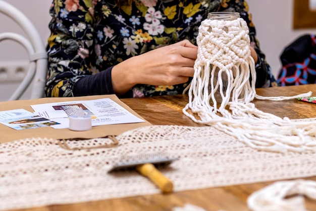 Jovem macramê branco tecendo com macramê para decoração em uma oficina