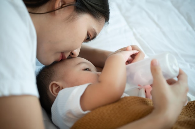 Jovem mãe abraçando seu filho recém-nascido para embalar o bebê para dormir enquanto bebe leite