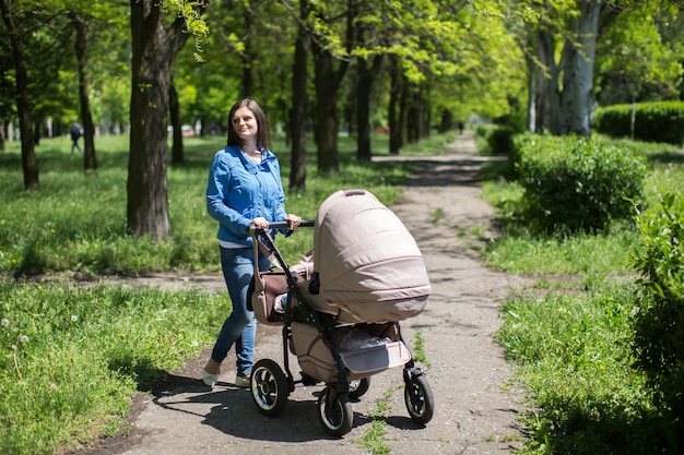 Jovem mãe andando um carrinho no parque