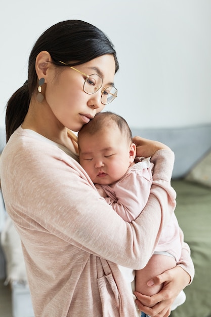 Foto jovem mãe asiática abraçando sua filha e amando-a enquanto ela dormia sobre as mãos