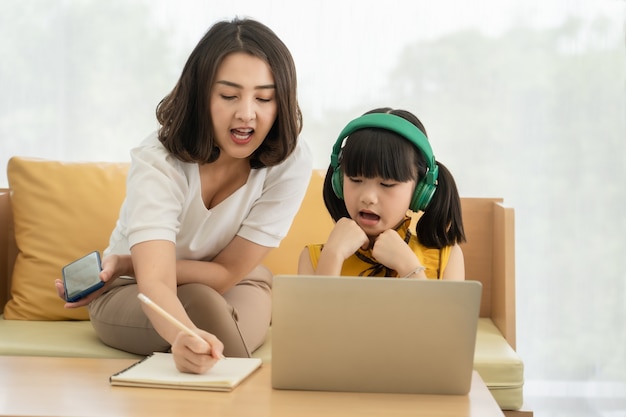 Jovem mãe asiática com laptop ensinando criança a homeme