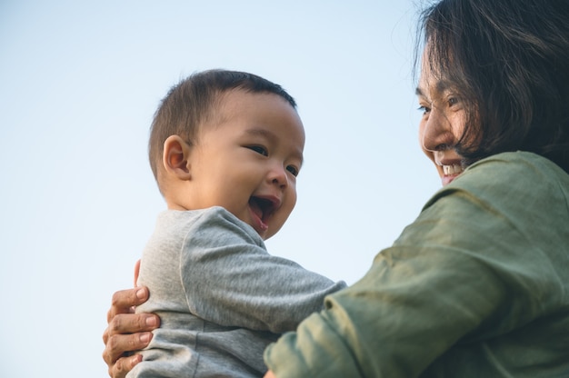 Foto jovem mãe asiática com seu filho ou bebê fofo no parque em casa.