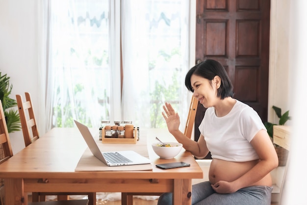 Jovem mãe asiática faz videochamada para conversar com a família no laptop