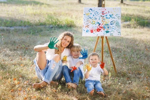 Jovem mãe atraente se divertindo com seus filhos no parque. família alegre se divertindo ao ar livre. mãe brinca com seus filhos.