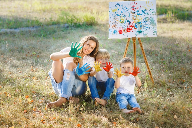 Jovem mãe atraente se divertindo com seus filhos no parque. família alegre se divertindo ao ar livre. mãe brinca com seus filhos.