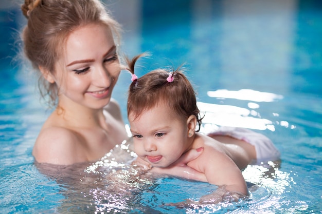 Jovem mãe banha o bebê na piscina.