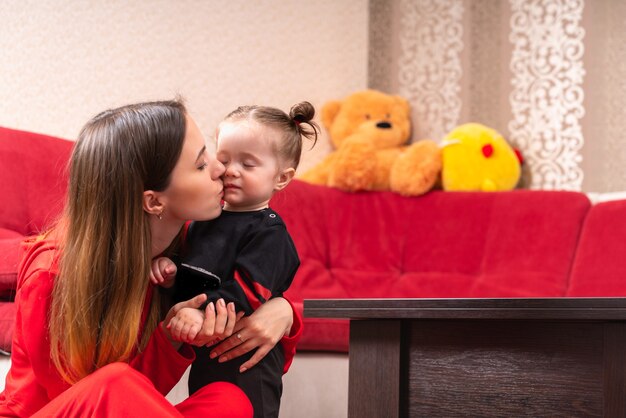 Jovem mãe beijando sua filhinha em casa