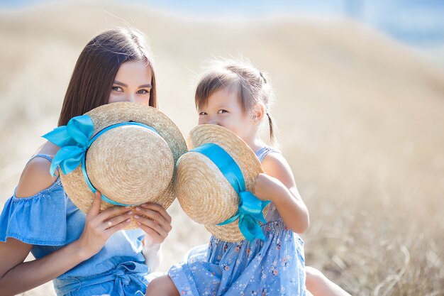 Jovem mãe bonita e sua filha ao ar livre. Closeup retrato de família feliz no campo de natureza selvagem. Garotas se divertindo.