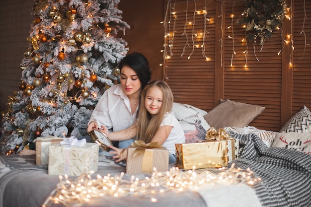 Jovem mãe bonita e sua filha compartilhar presentes de natal