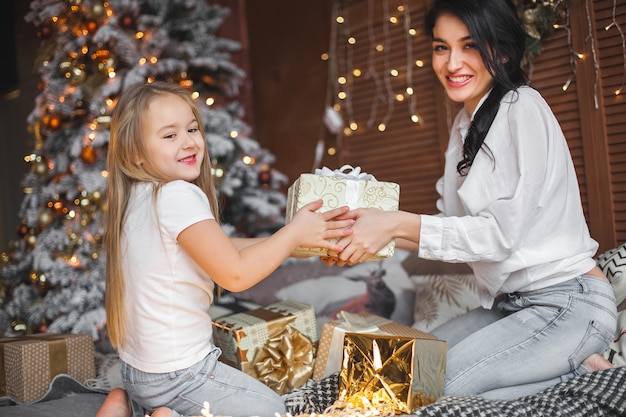 Jovem mãe bonita e sua filha compartilhar presentes de Natal