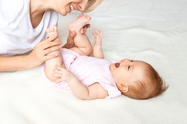 Jovem mãe brincando com o bebê na cama, close-up.