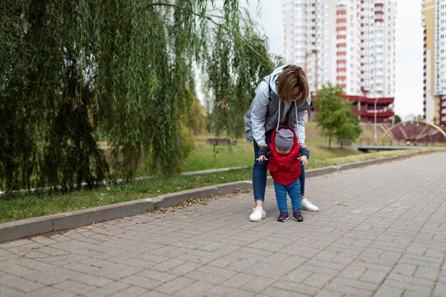 Jovem mãe caminha com seu filho pequeno no parque