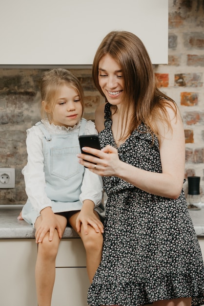 Foto jovem mãe com a filha na cozinha