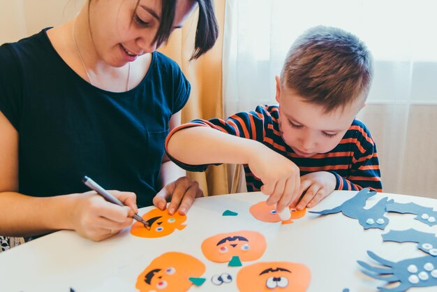 Jovem mãe com filho criança fazendo abóboras artesanais para o feriado de halloween