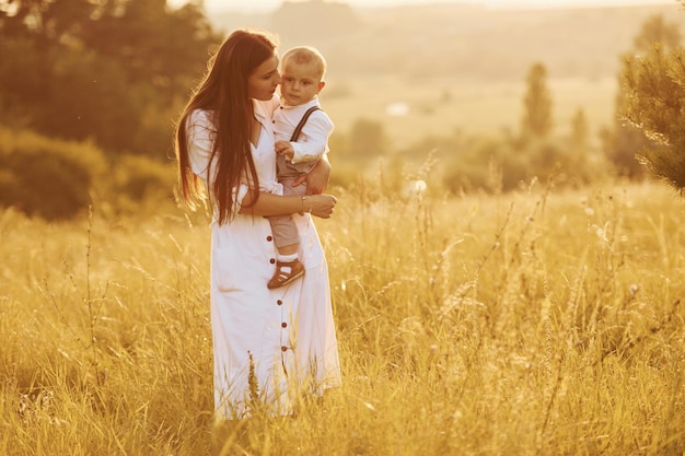 Jovem mãe com seu filho pequeno está ao ar livre no campo agrícola lindo sol