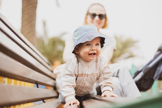 Foto jovem mãe com seu lindo bebê bebê no banco do parque infantil urbano em aquecimento